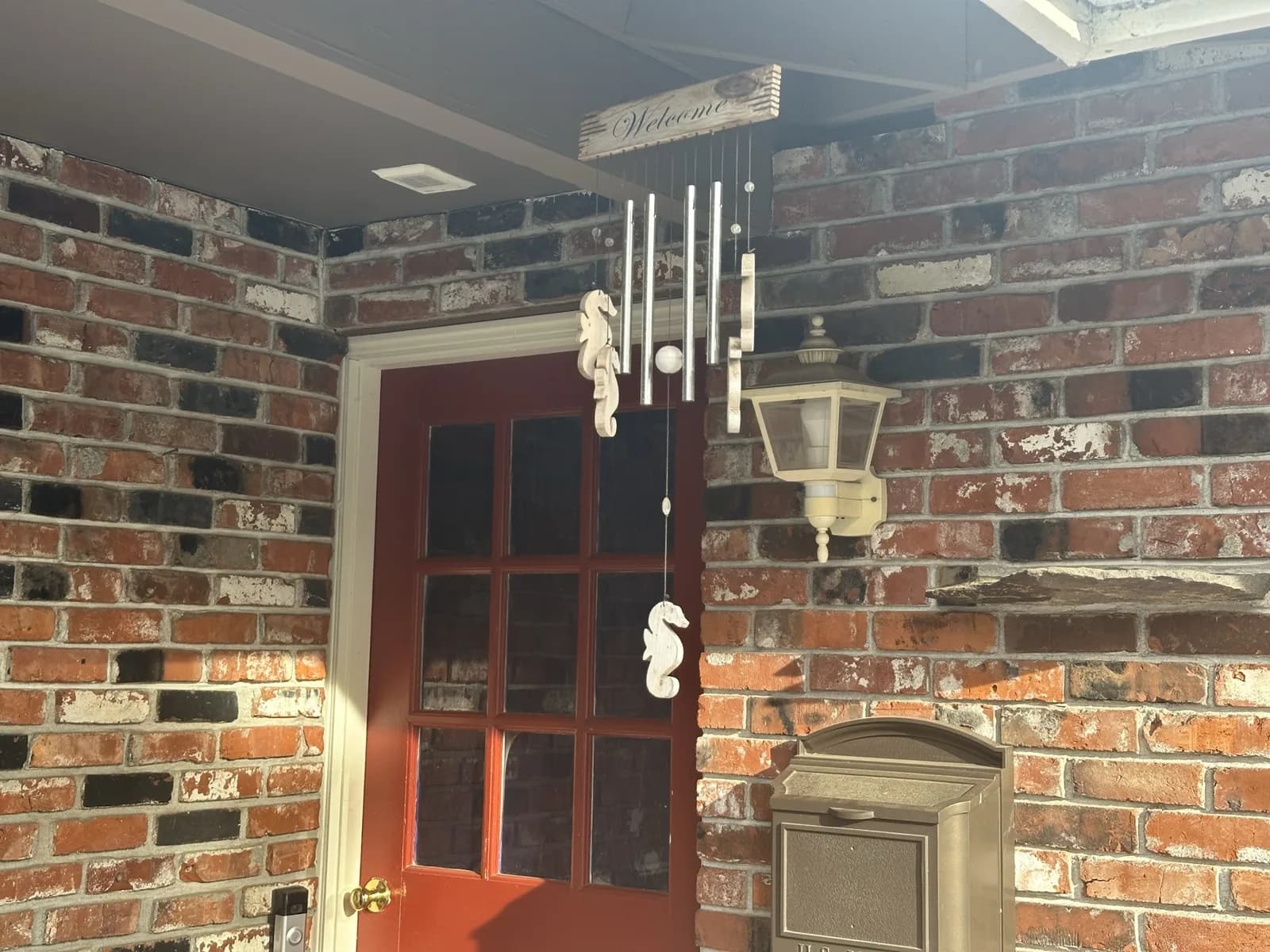 Red entrance door, brick walls, and hanging wind chimes on Angel Light’s covered porch.