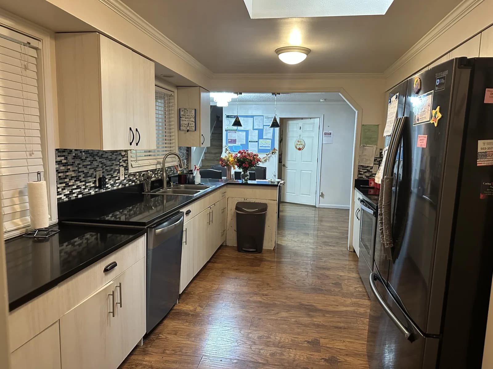 Angel Light kitchen with cream cabinets, dark countertops, and a stainless steel refrigerator.
